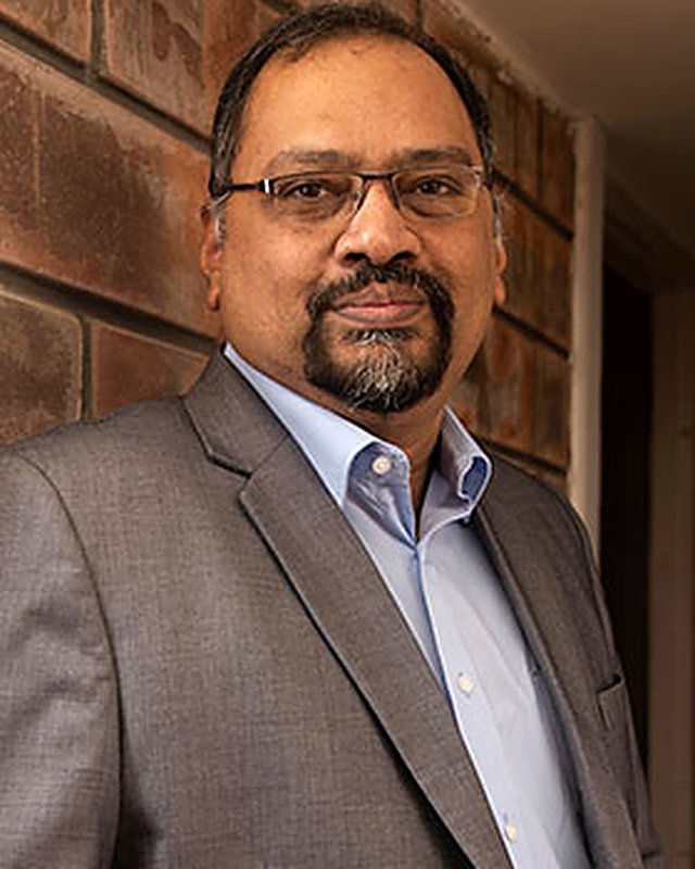 Portrait of Abhik Biswas in a gray suit and light blue shirt